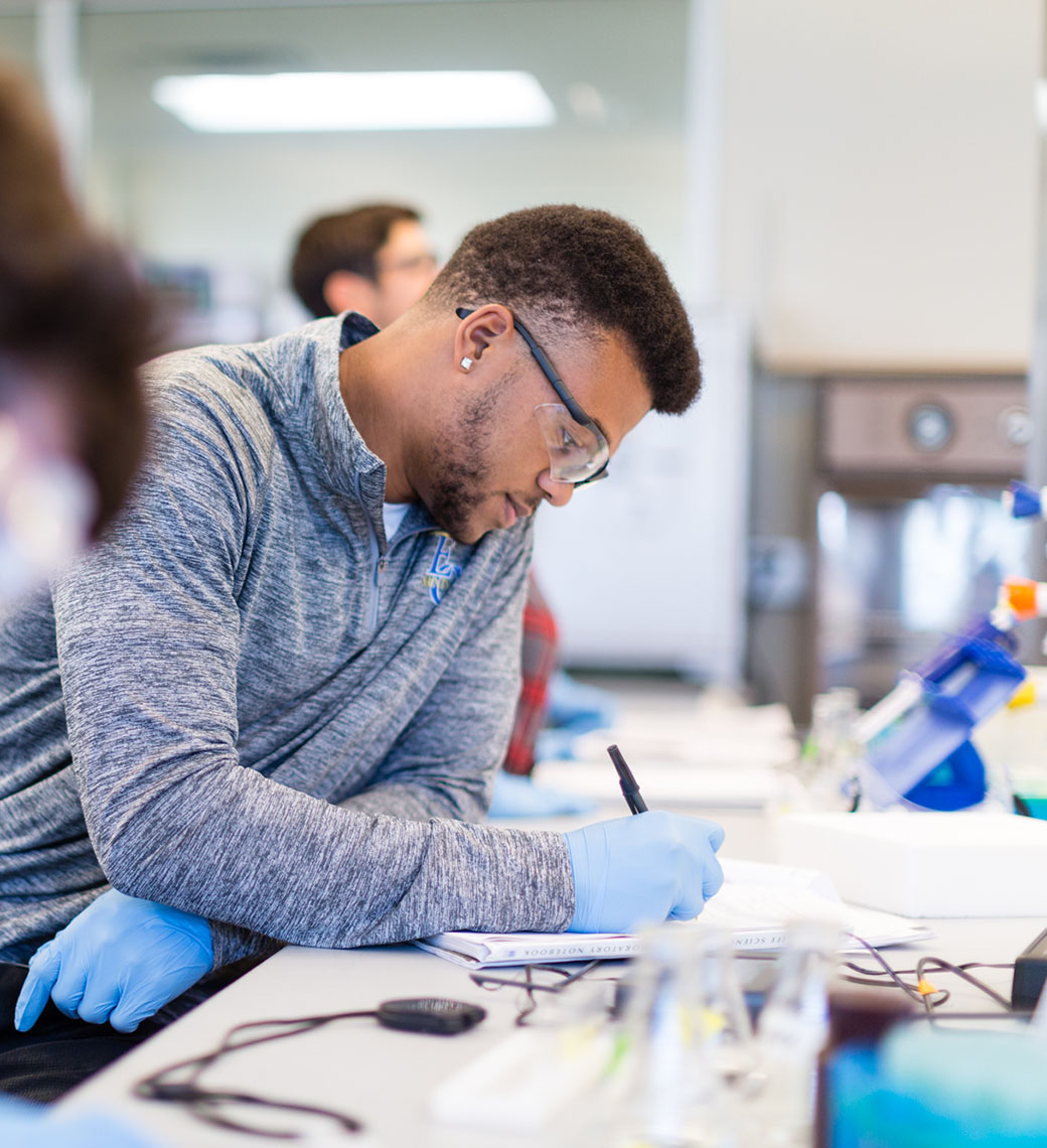 Emmanuel College male nursing student working in lab.