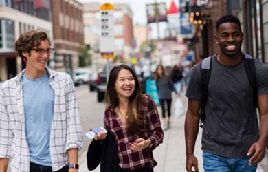 Smiling Emmanuel college students walking on the sidewalk